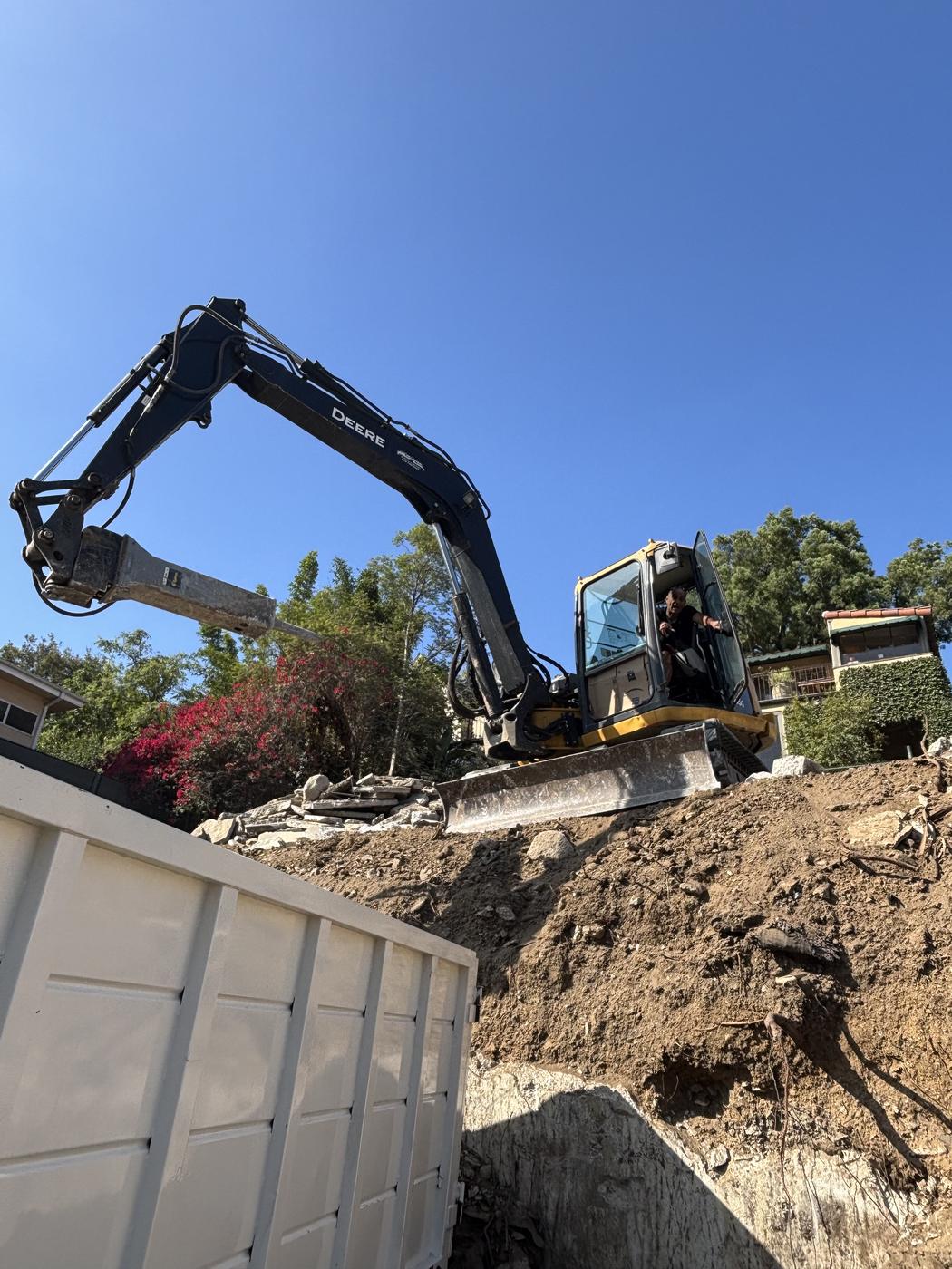 Excavator loading debris into dumpster